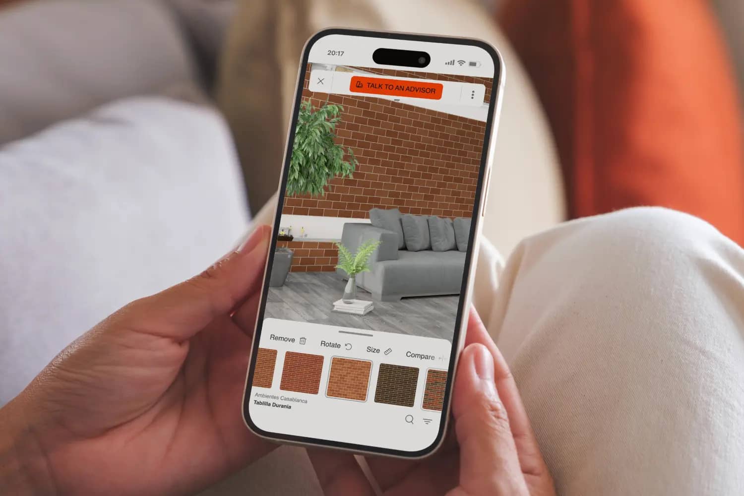 Shopper holding phone, with screen showing Roomvo room visualizer on Ambientes Casablanca website.